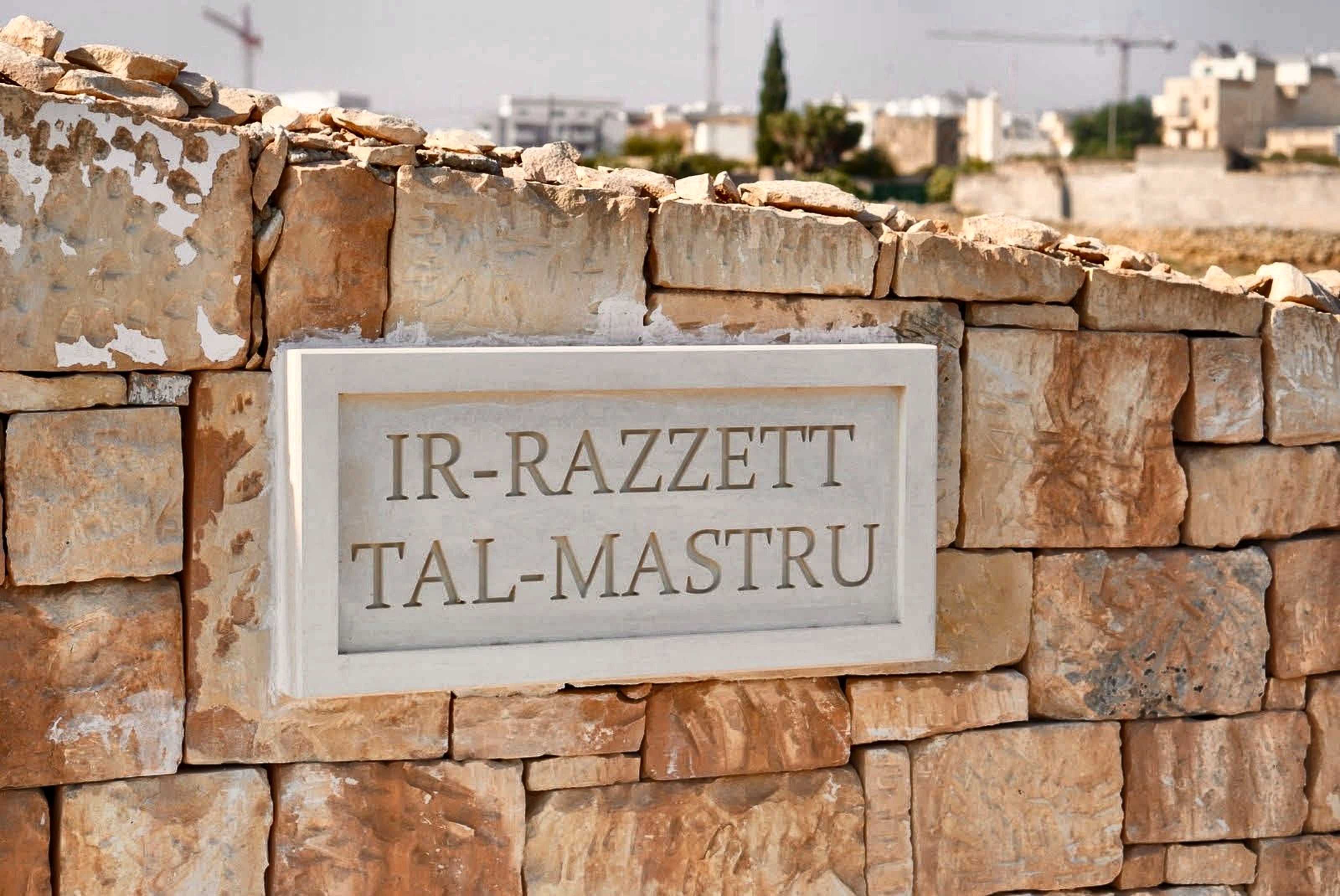 Hand-carved limestone plaque at the entrance wall of Ir-Razzett tal-Mastru