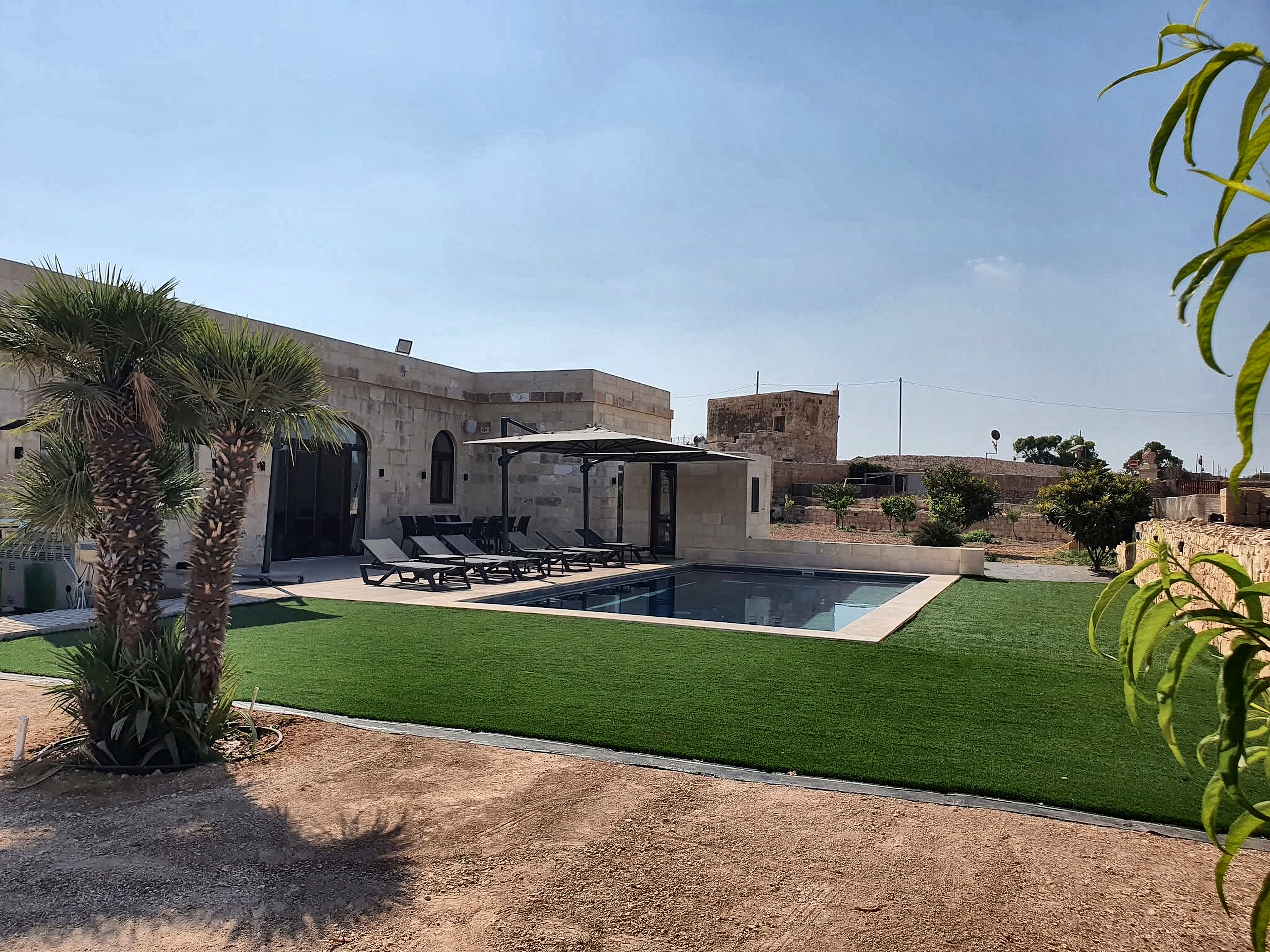 Traditional Maltese farmhouse architecture with private pool and mature palm trees