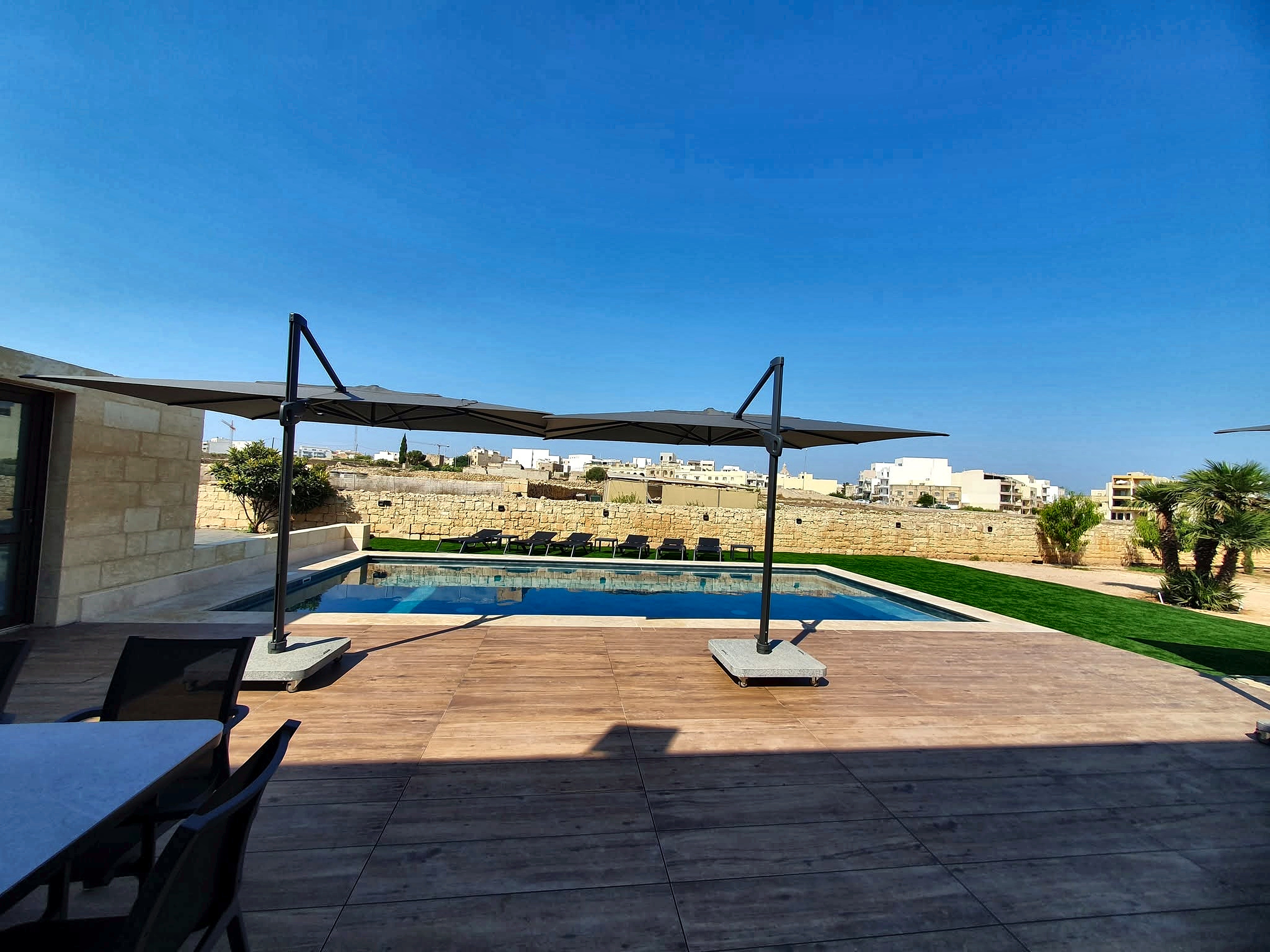 Wide sunny panoramic view across the private swimming pool and sun deck