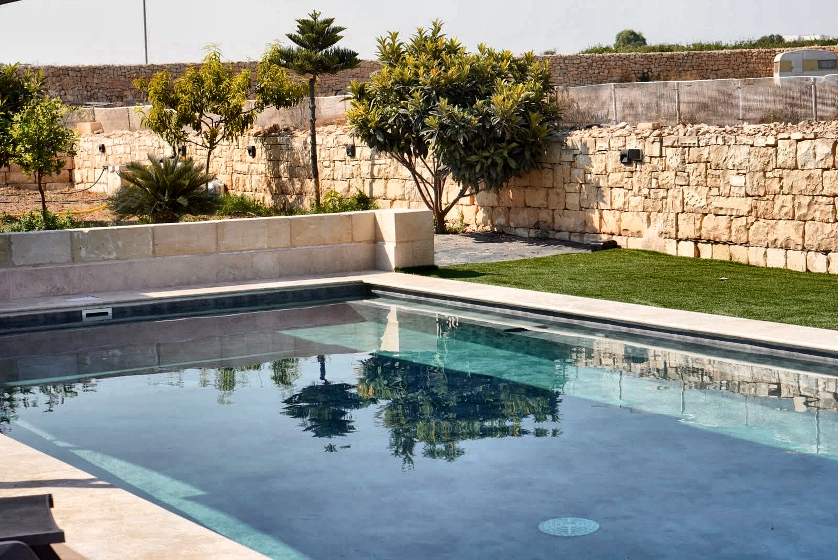 Crystal blue freshwater pool reflecting Mediterranean greenery